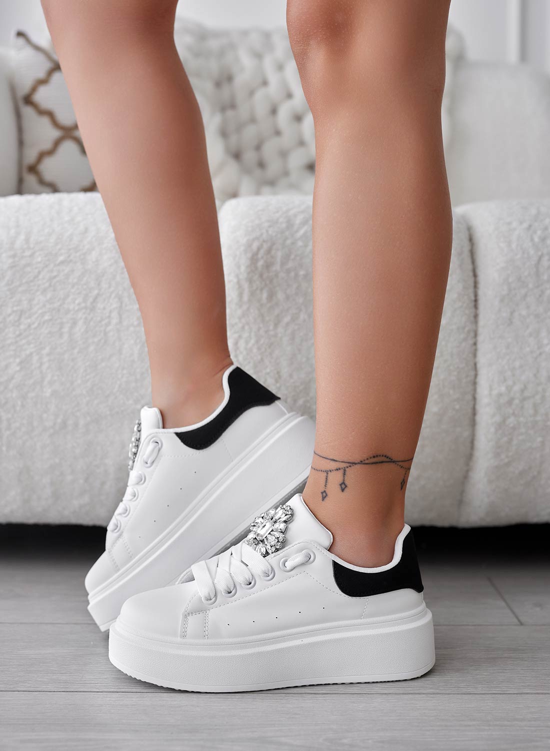 White sneakers with black heel and jewel