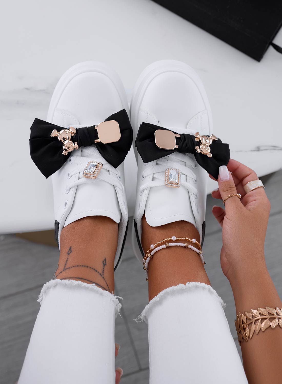 Sneakers bianche con fiocco nero e spilla teddy oro