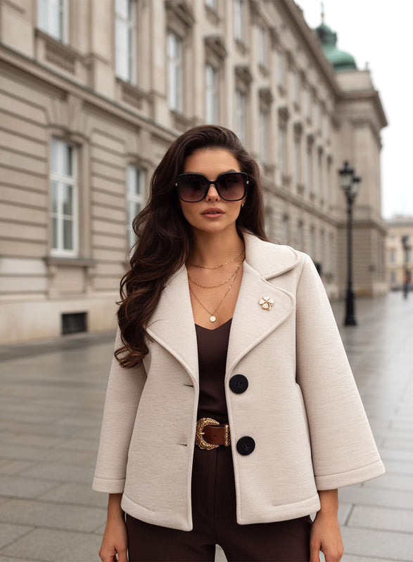 Beige short coat with black buttons and brooch